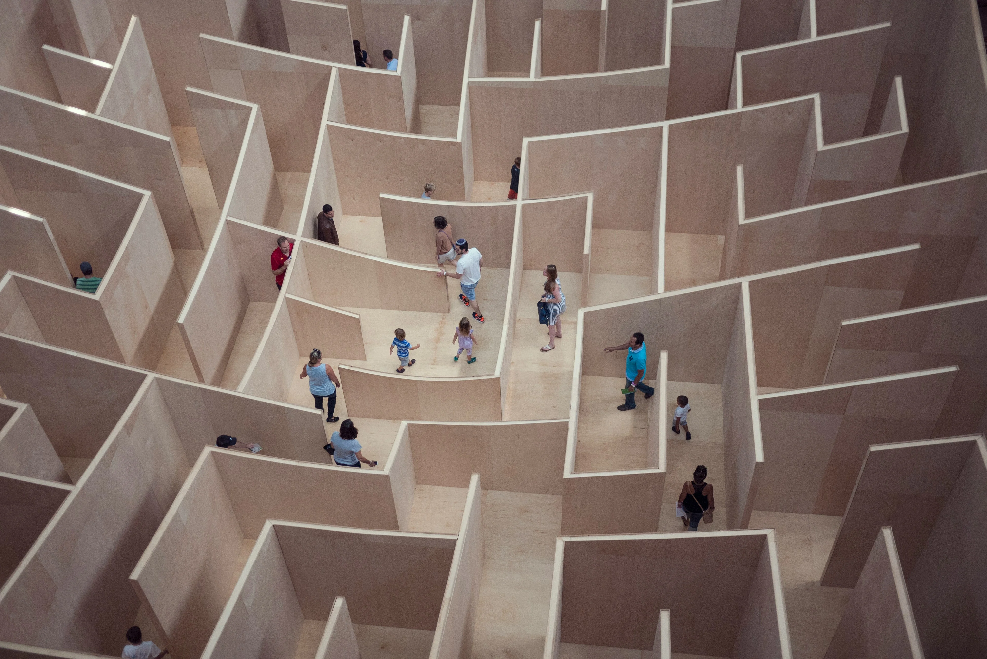 Overhead view of people navigating a large wooden maze